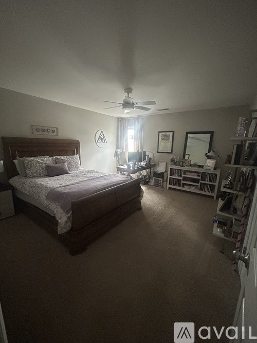 A bedroom with a bed, dresser, and a ceiling fan.