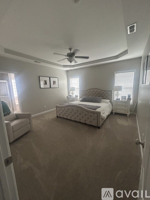 A bedroom with a large bed and a ceiling fan.
