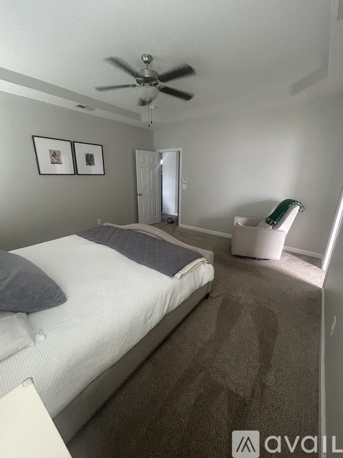 A bedroom with a bed, a ceiling fan, and two pictures on the wall.