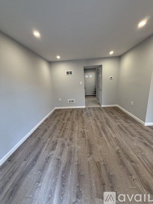 A room with wooden flooring and a door in the background.