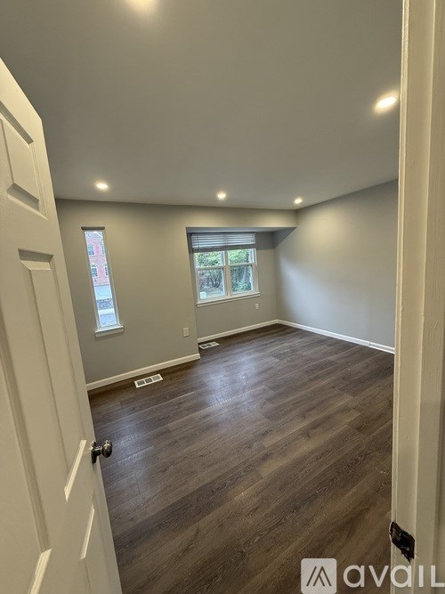A room with wooden flooring and a door on the left.