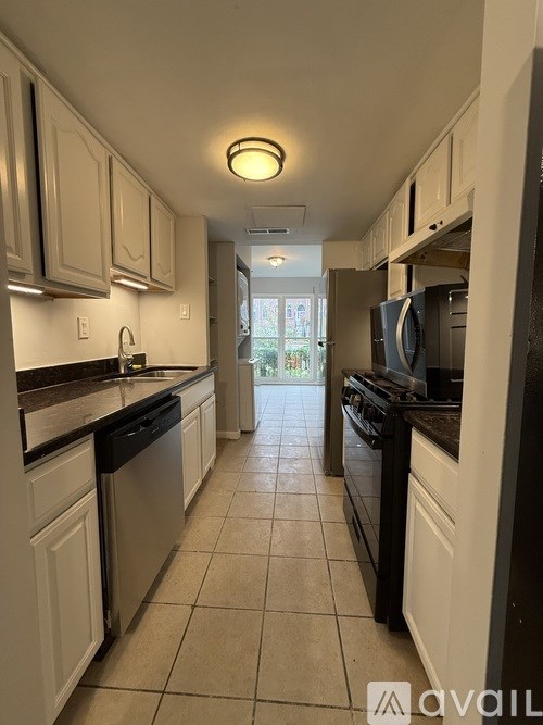 A kitchen with black appliances and white cabinets.