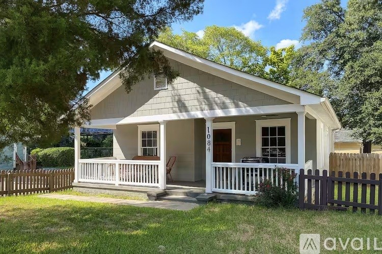 A house with a porch and a fence in front of it.