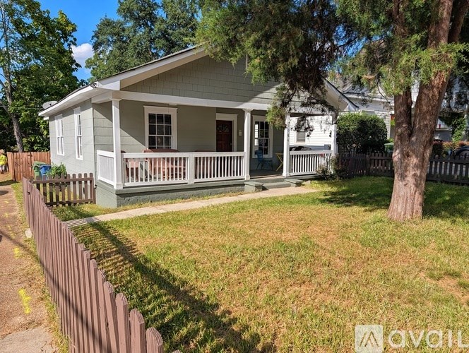 A house with a porch and a fence in front of it.