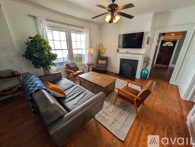 A living room with a grey couch, a wooden coffee table, a fireplace, and a ceiling fan.