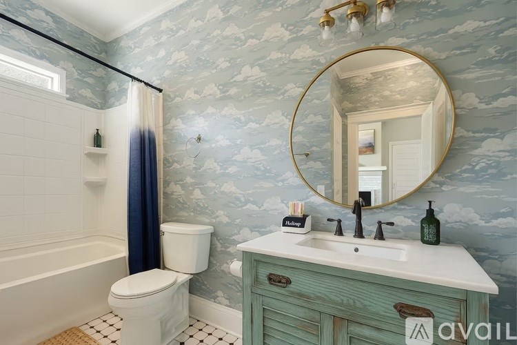 A bathroom with a blue and white wallpaper and a round mirror.