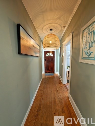 A long hallway with a wooden floor and a light hanging from the ceiling.