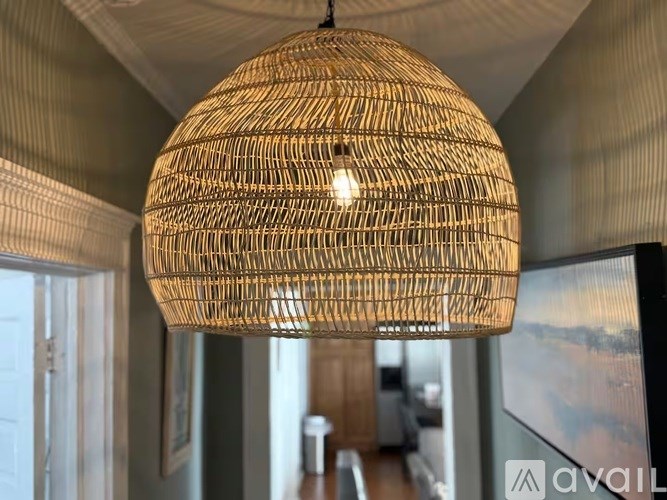 A large, round, woven lamp hangs from the ceiling in a room.