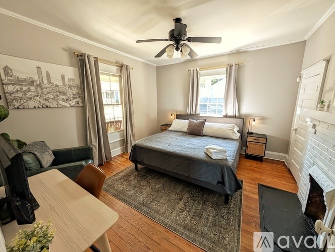 A bedroom with a bed, a chair, a table, and a fireplace.