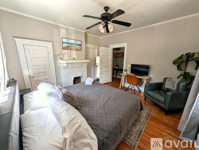 A bedroom with a bed, a chair, and a painting on the wall.
