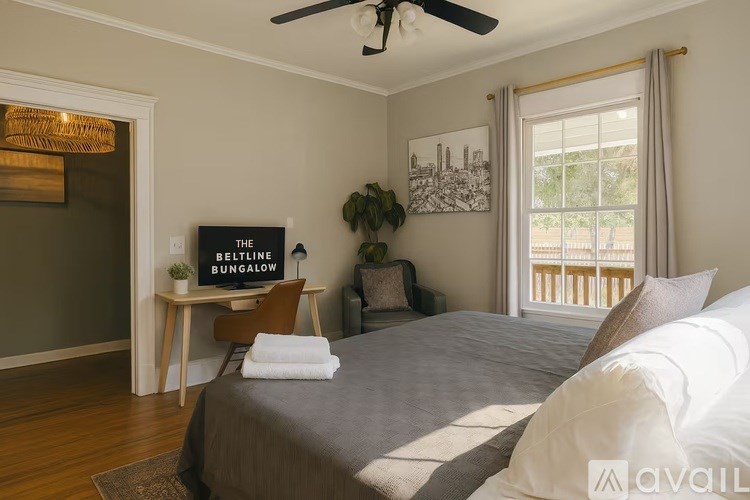 A bedroom with a bed, a chair, a table, and a plant.