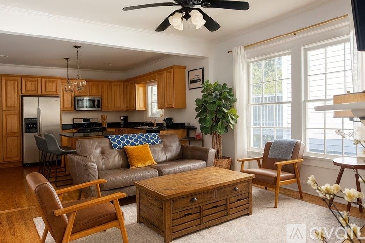 A living room with a brown leather couch, wooden coffee table, and a ceiling fan.