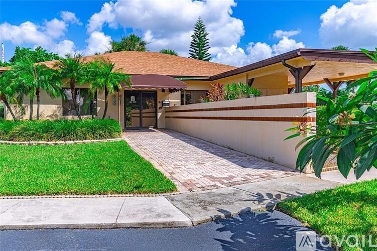 A house with a driveway and a palm tree in front.