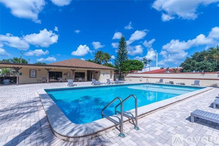 A large outdoor swimming pool surrounded by a tiled patio and lounge chairs.
