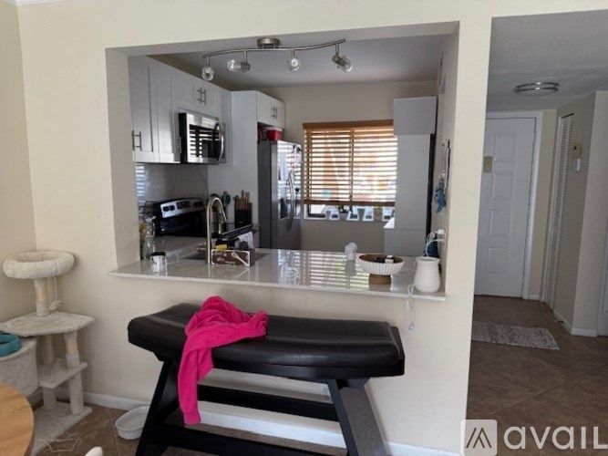A black massage table with a pink towel on it sits in front of a mirror in a room.