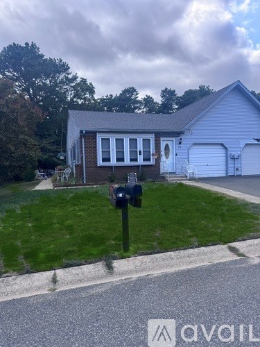 A house with a white garage door and a mailbox on the lawn.