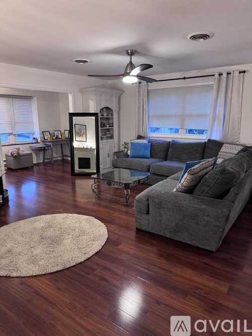 A living room with a grey couch and a rug.