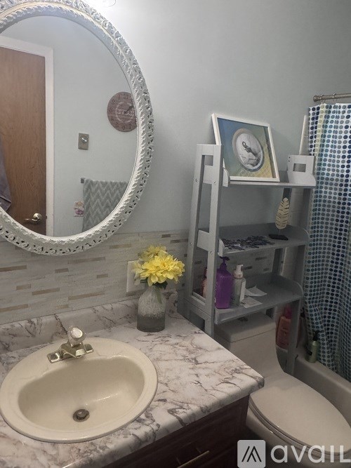 A bathroom with a marble countertop and a round mirror.