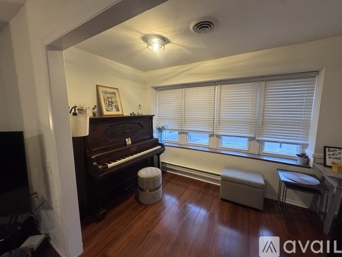 A room with a piano and a window with blinds.