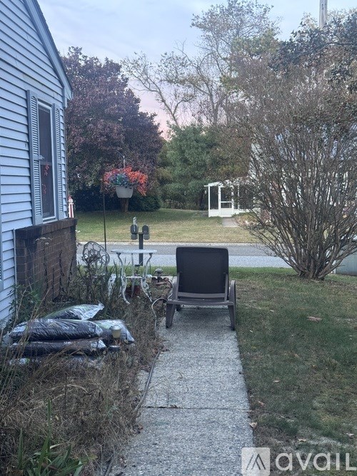 A backyard with a chair, a small table, and a pile of bags.