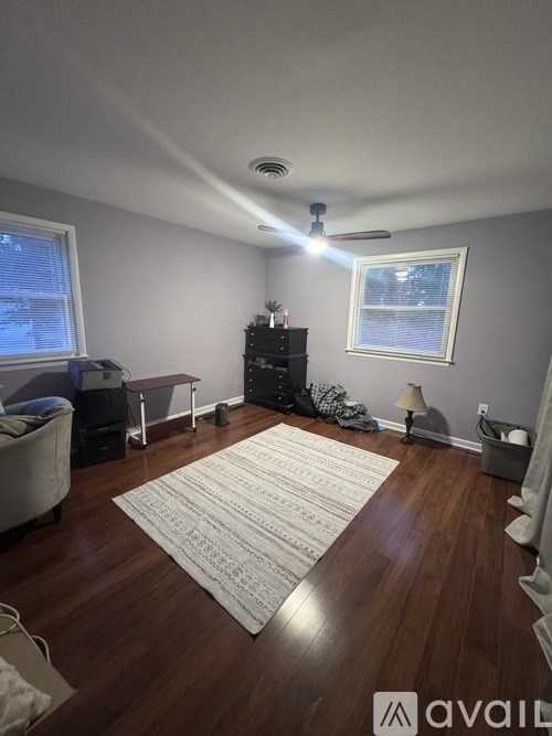 A living room with a rug on the floor and a ceiling fan above.