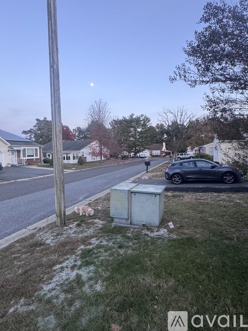 A street view with a car parked on the side and a utility box in the foreground.