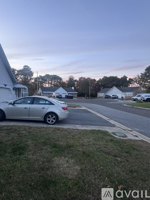 A silver car is parked on the side of a road.