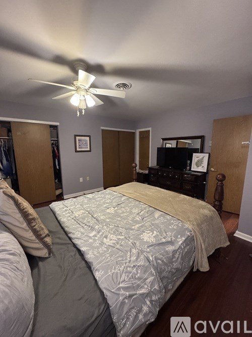 A bedroom with a bed, dresser, and ceiling fan.