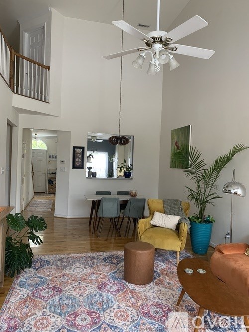 A living room with a rug, chairs, and a ceiling fan.