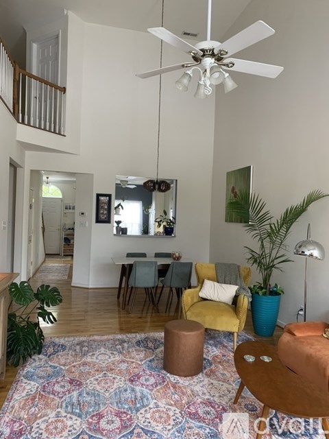 A living room with a rug, chairs, and a ceiling fan.