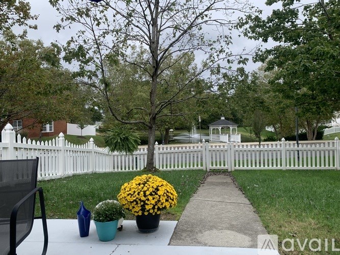 A white picket fence with a tree and flowers in front.