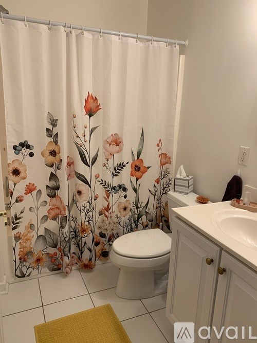 A bathroom with a floral shower curtain and a white toilet.