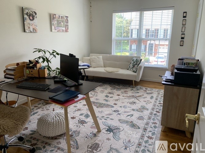 A room with a desk, chair, couch, and a rug.