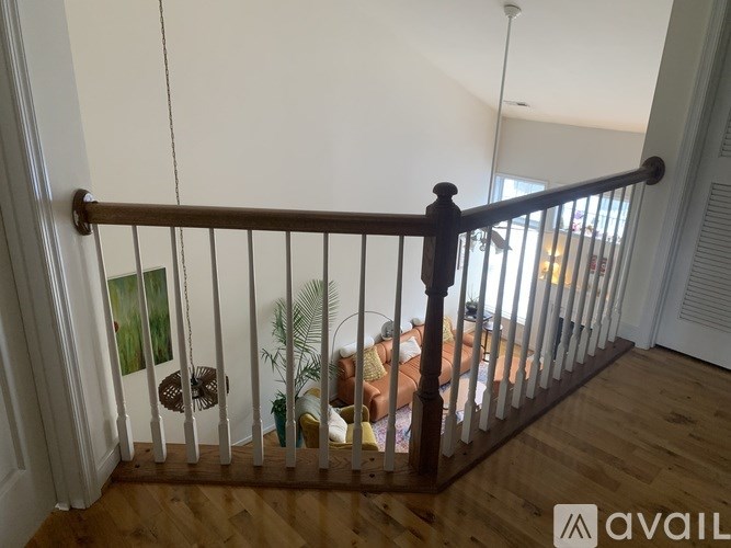 A balcony with a wooden railing and a view of a living room.