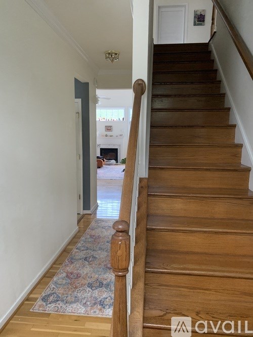 A staircase with a wooden handrail and a patterned rug on the floor.