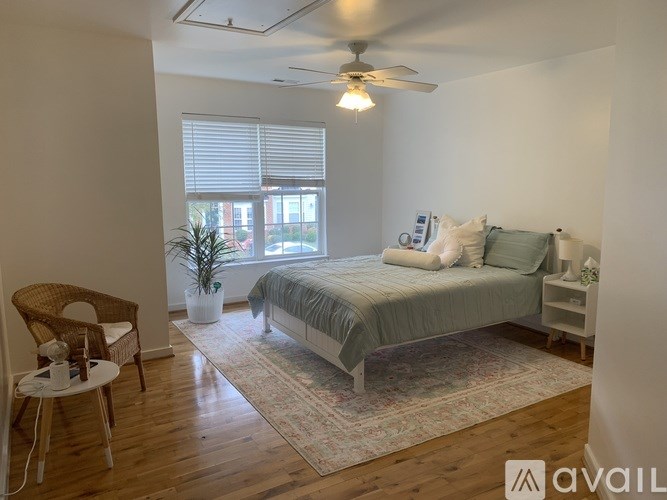A bedroom with a bed, chair, and potted plant.