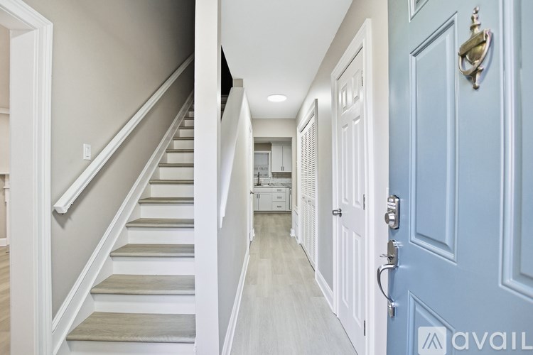 A hallway with a blue door and a staircase on the left.