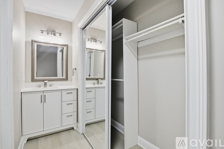 A white bathroom with a mirror and a cabinet.