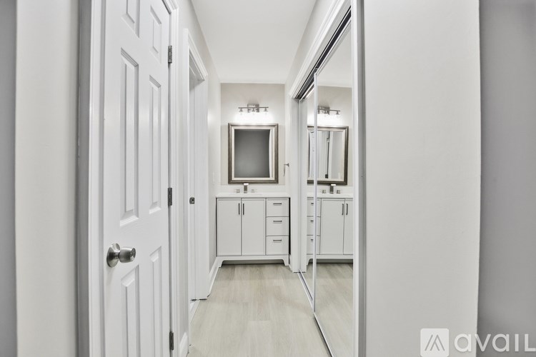 A hallway with a white door and a mirror on the wall.