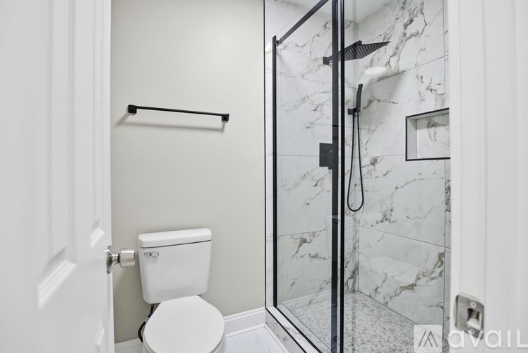 A white toilet is in a bathroom with a marble wall.