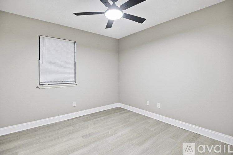 A room with a ceiling fan and a window with blinds.