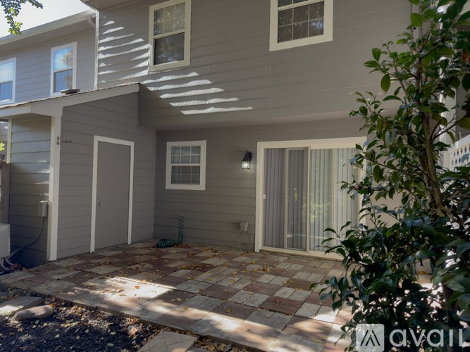 A house with a grey siding exterior and a patio with a brick pattern.