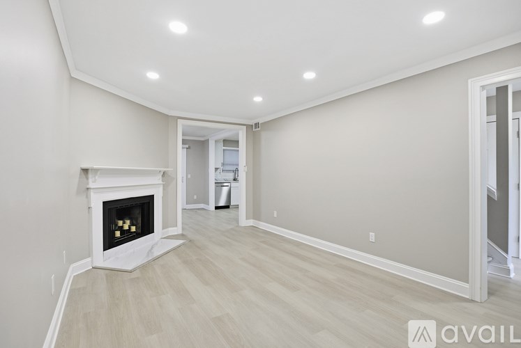 A spacious room with a fireplace and wooden flooring.