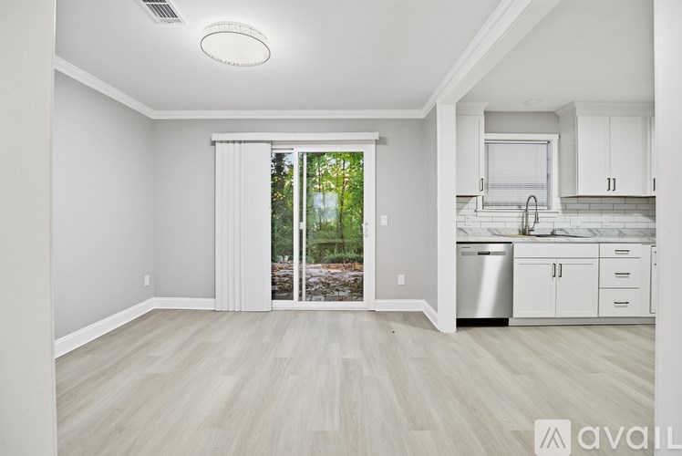 A kitchen with white cabinets and a dishwasher is visible through a sliding glass door.