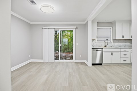 A kitchen with white cabinets and a dishwasher is visible through a sliding glass door.