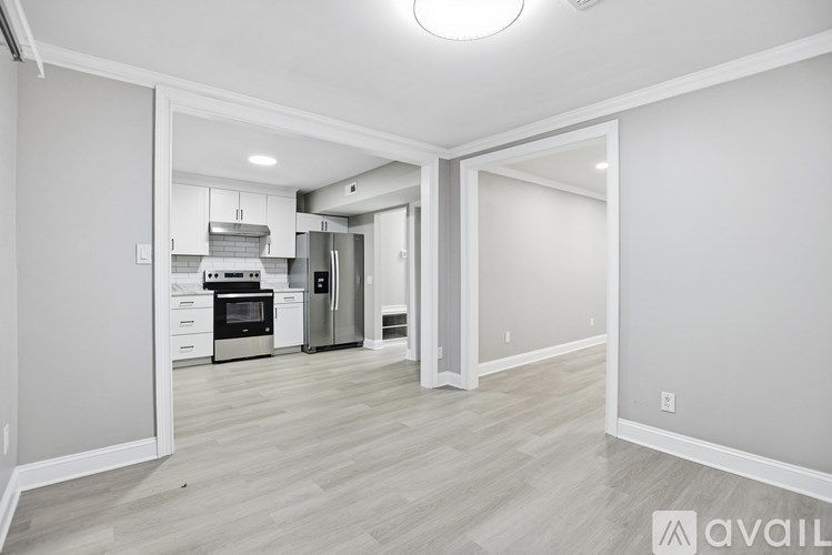 A spacious kitchen with white cabinets and stainless steel appliances is visible through the open door.