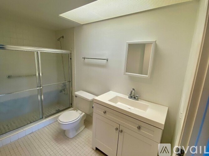 A white bathroom with a toilet, sink, and shower.