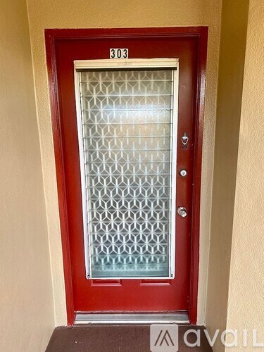 A red door with a glass window and a number 303 on it.