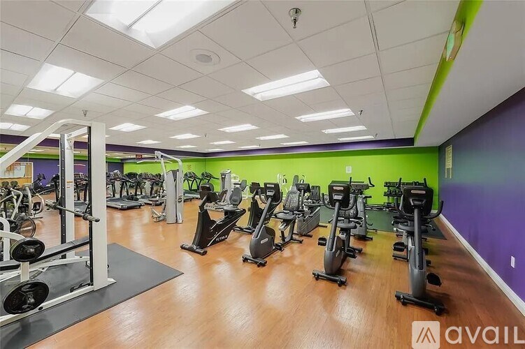 A gym with a variety of exercise equipment including treadmills, stationary bikes, and weight machines.
