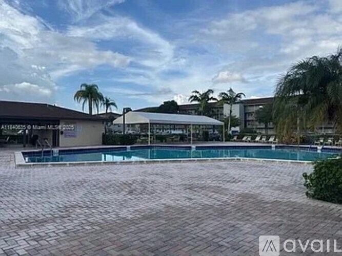 A pool surrounded by a brick patio with a building in the background.